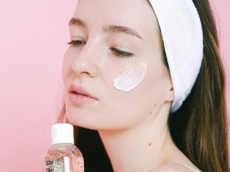 woman with serum, under-eye patch, skincare products